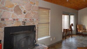 A stone fireplace, wooden ceiling, and a dining area with chairs. - Updated Cottage on 6+ wooded acres, Horse setup, RV Hookups, Secluded not remote (Valley Springs)
