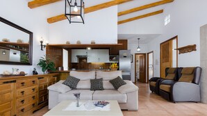 Una sala de estar con sofá, mesa de centro y comedor, con una cocina al fondo.