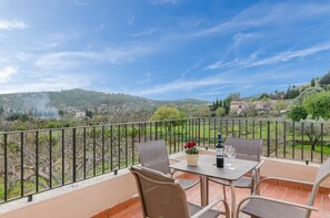 Une terrasse avec une table et des chaises, un pot de fleurs et une bouteille de vin.