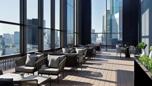 A modern rooftop lounge with wicker furniture, a small table, and potted plants. - AC Hotel by Marriott Tokyo Ginza (Tokyo)