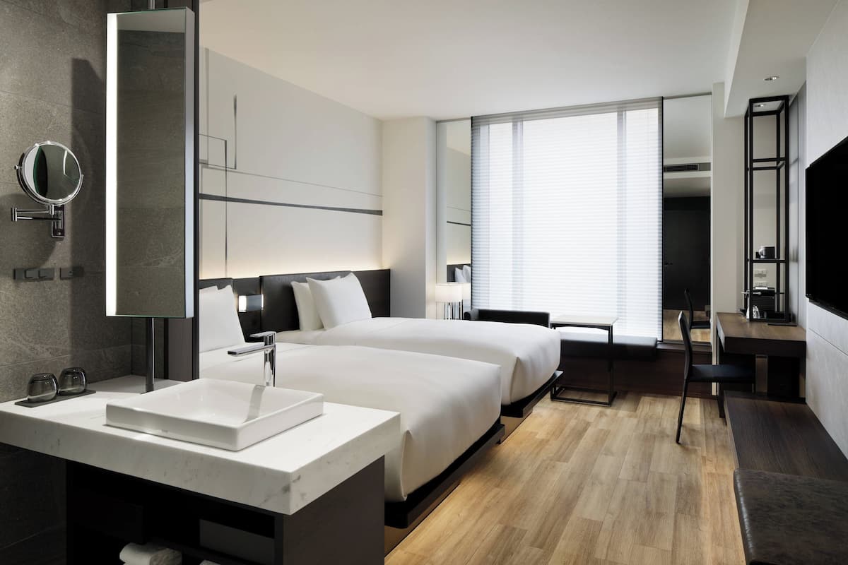 Een moderne hotelkamer met een groot bed, een nachtkastje, een ingebouwde televisie en een groot raam.
