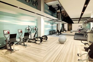 A modern gym with various exercise equipment, including treadmills, elliptical machines, and stationary bikes.
