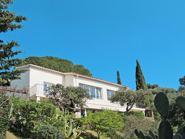 A two-story house with a white facade, large windows, and a balcony.
