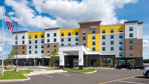 Un hôtel à plusieurs étages au design moderne, doté d’une entrée imposante et d’un parking.