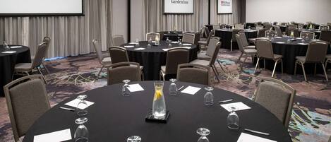 A conference room at Hilton Garden Inn with multiple tables, chairs, and presentation screens.