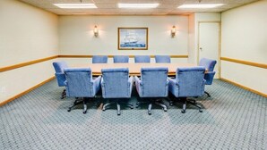 A conference room with a long table and six chairs, a framed picture on the wall, and two wall-mounted lamps. - Rodeway INN Rockford (Rockford)
