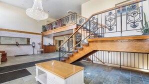 A spacious lobby with a wooden staircase, a chandelier, and a white reception desk. - Rodeway INN Rockford (Rockford)