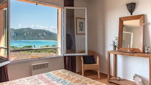 Un dormitorio con un amplio ventanal que ofrece vistas a un paisaje costero.