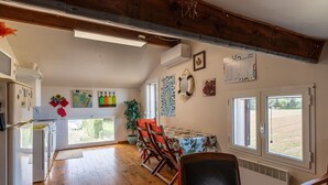 Une cuisine avec un plancher en bois, un coin repas avec une table et des chaises, et une vue sur l’extérieur.