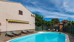 Une piscine avec des chaises longues et un espace abrité.