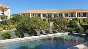 A hotel with a pool, surrounded by greenery and a clear blue sky. - Cosy apartment for 2 guests with pool, A/C, WIFI and terrace (Calvi)