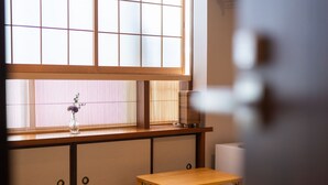A traditional Japanese room with tatami flooring, a low wooden table, a shoji screen window, and a radiator. - Oyado Kien (Tokyo)
