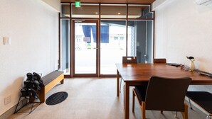 A conference room with a wooden table, chairs, and a bench. There is a shoe rack and a manhole cover on the floor. - Oyado Kien (Tokyo)