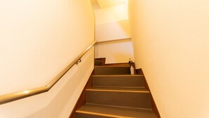 A narrow staircase with wooden steps and a metal handrail, leading upwards. - Oyado Kien (Tokyo)