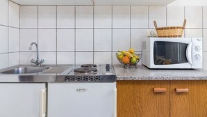 A kitchen with white cabinets, a stainless steel sink, a microwave, and a small refrigerator. - Cosy apartment for 3 guests with pool, A/C, WIFI, TV and terrace (Porec)