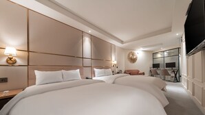 A hotel room with two large beds, a desk with a lamp, a TV, and a seating area with chairs. - Songpa Boutique Hotel XYM (Seoul)