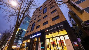 A modern building with a large glass facade and a store named 'YOGERPRESSO' at the ground level. - Songpa Boutique Hotel XYM (Seoul)