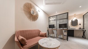A modern room with a pink sofa, a marble table, a large mirror, and a desk with two monitors. - Songpa Boutique Hotel XYM (Seoul)