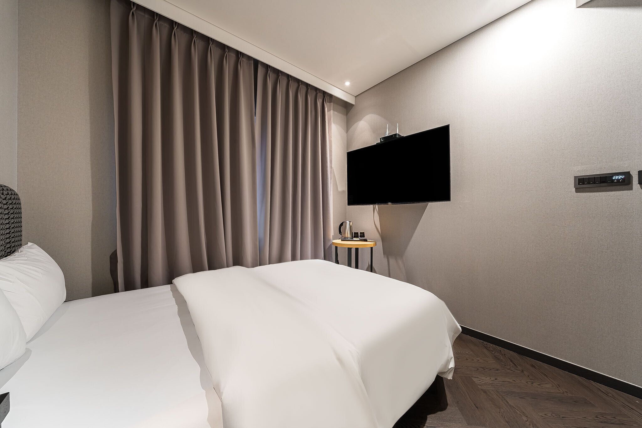 Une chambre d’hôtel avec un grand lit, un téléviseur à écran plat fixé au mur et une petite table avec une bouilloire.