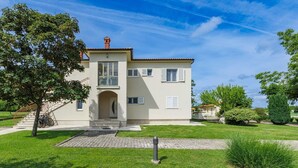 A two-story house with a front entrance, a staircase, and a well-maintained lawn. - Nice apartment for 8 guests with A/C, WIFI, pool, TV and terrace (Pazin)