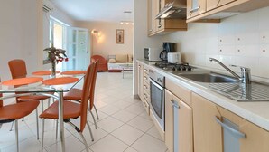 A modern kitchen with a dining area, featuring stainless steel appliances, wooden cabinets, and orange chairs. - Nice apartment for 8 guests with A/C, WIFI, pool, TV and terrace (Pazin)