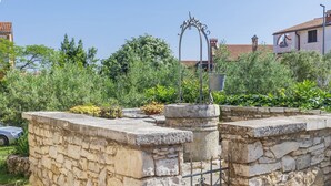 Un mur de pierre agrémenté d’un portail en métal et d’une arche décorative également en métal.
