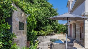 Un espace patio aménagé avec des meubles en osier, une petite piscine et un mur en pierre.
