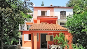 A two-story house with a tiled roof, a balcony, and a small garden area with outdoor furniture. - Beautiful apartment for 3 guests with WIFI, A/C, TV, terrace and pets allowed (Rovinj)
