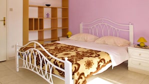 A bedroom with a white metal bed frame, a patterned bedspread, a wooden shelf unit, a nightstand with a lamp, and a white dresser. - Beautiful apartment for 3 guests with WIFI, A/C, TV, terrace and pets allowed (Rovinj)
