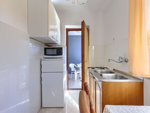 Une cuisine compacte équipée d’un four à micro-ondes, d’un réfrigérateur, d’un évier et de meubles de rangement en bois.