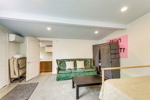 A room with a green sofa, a wooden bed frame, a small table, a wardrobe, and a door leading to a kitchen. - Walk to the Beach! Spacious 6BR La Jolla Home (La Jolla)