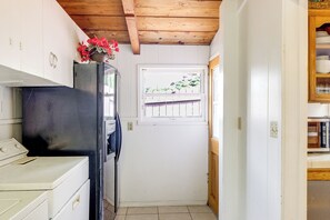A narrow kitchen with a black refrigerator, a window with a view of greenery, and a wooden ceiling. - Walk to the Beach! Spacious 6BR La Jolla Home (La Jolla)