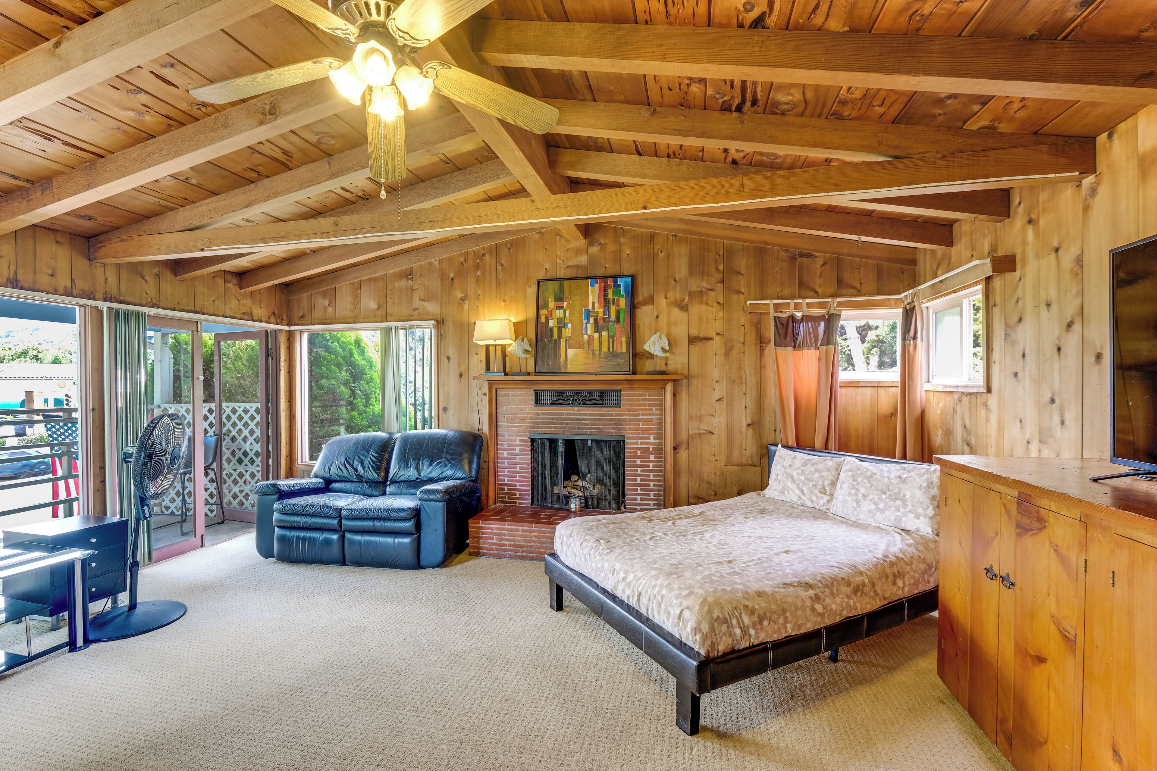 L’intérieur d’un chalet en bois comprend un lit, une cheminée, un canapé en cuir et un coin repas.