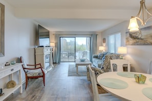 Relax in this open-plan living space with a sliding glass door leading to an outdoor area, a dining table, and comfortable seating.