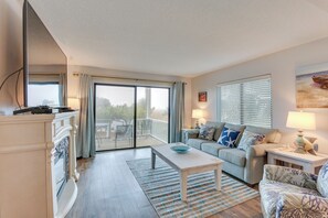 Relax in this stylish living room with a fireplace, comfortable sofa, and balcony access.