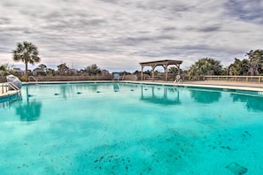 Piscina cristallina con bordo in legno e gazebo.