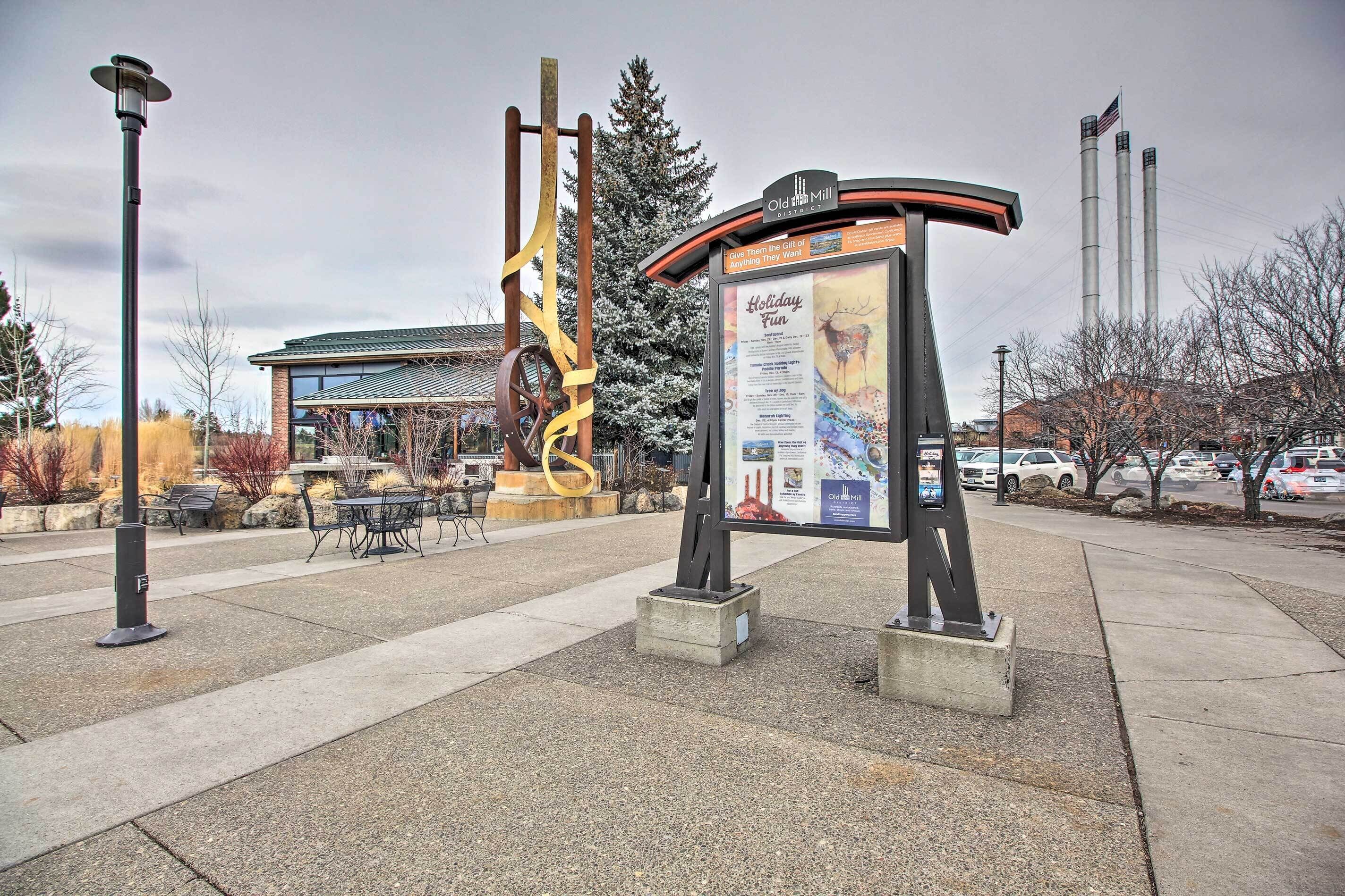 A public square with a large informational sign, a street lamp, and a sculpture.