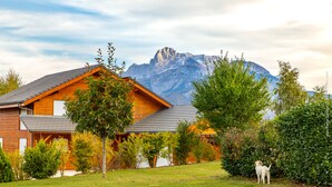 Une maison en bois avec un toit en pente, entourée d’une pelouse bien entretenue et d’une végétation dense.