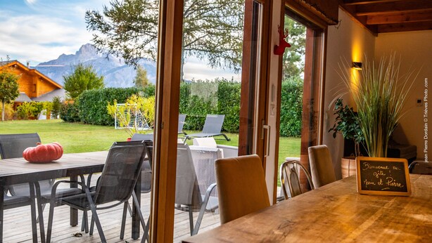 Une terrasse en bois avec une table et des chaises, une citrouille rouge et une pancarte avec du texte en français.