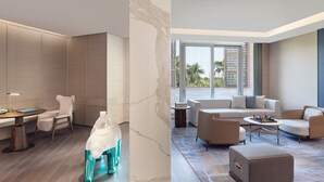 A modern hotel room with a marble wall, a dining area with a table and chairs, and a living area with sofas and a coffee table.
