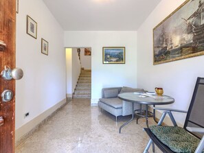 A hallway with a staircase, a sofa, a round table, and a chair.
