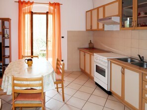 Compact kitchen with a stove, sink, and cabinets, adjacent to a dining area with a table and chairs.