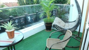 Ein Balkon mit einem kleinen Tisch, zwei Korbstühlen und Blumentöpfen.