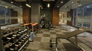 Un gimnasio con equipo de ejercicio, espejos y suelo a cuadros.