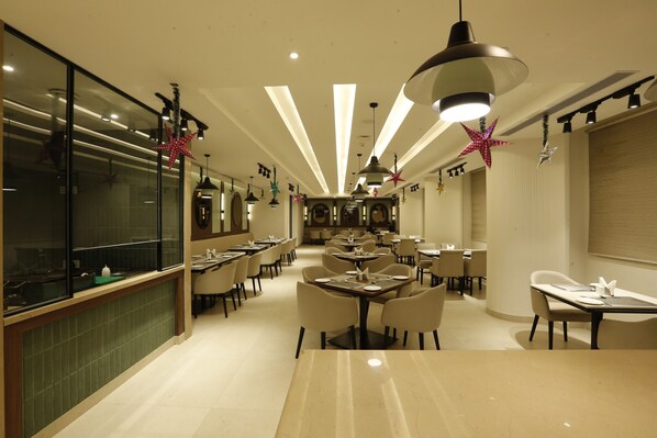 Un restaurante moderno con una barra larga, varias mesas para comer y decoraciones colgantes con forma de estrella.