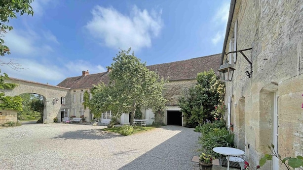 A courtyard with a gravel path, stone buildings, and outdoor seating. - Cozy house near Argentan - 9 guests (Sarceaux)