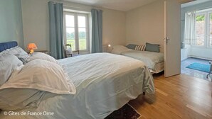 A bedroom with two beds, a window with curtains, a chair, and a view of the outdoors. - Cozy house near Argentan - 9 guests (Sarceaux)