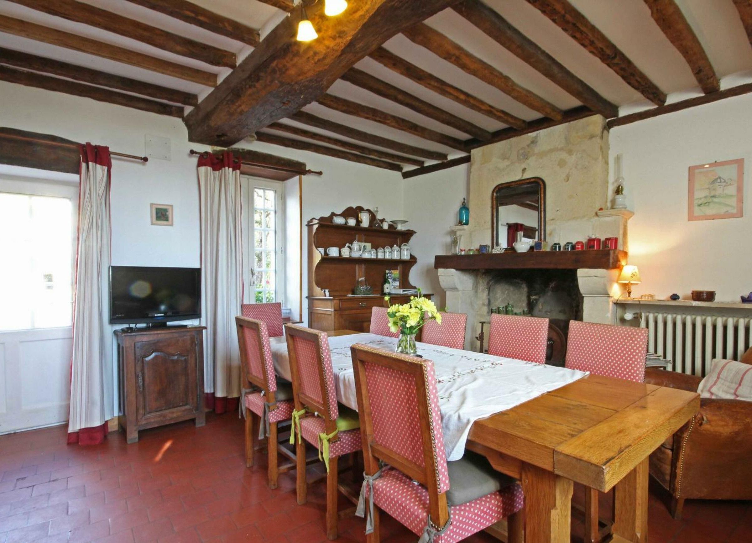 A dining area with a wooden table and chairs, a television, and a fireplace.