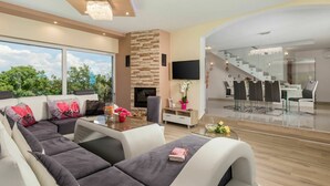 A modern living room with a sofa, a fireplace, a dining area with a glass table, and a staircase leading to another level. - Wonderful private villa for 8 people with private pool, WIFI, A/C, TV and patio (Pazin)