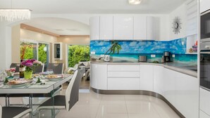 A modern kitchen with white cabinets, a curved island, and a tropical beach backsplash. - Wonderful private villa for 8 people with private pool, WIFI, A/C, TV and patio (Pazin)